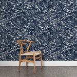A wooden chair stands in front of a wall papered in a playful wave print in white on a navy watercolor field.