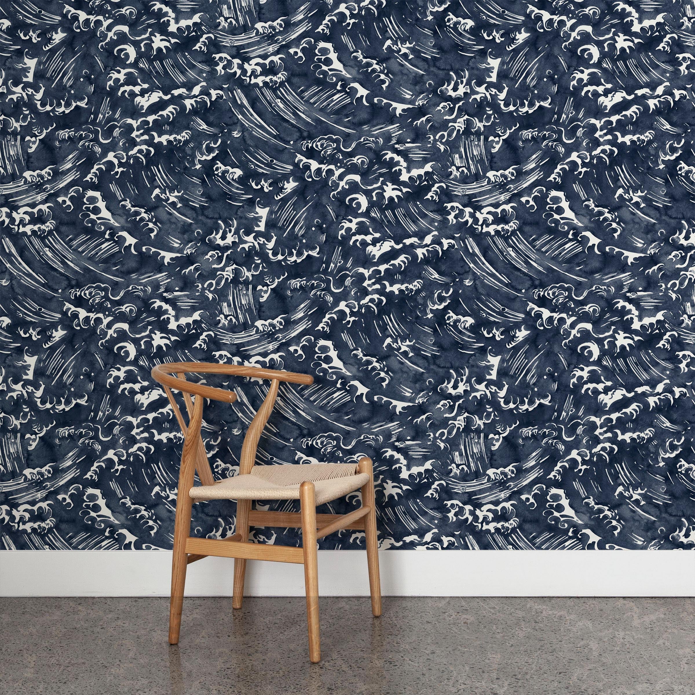 A wooden chair stands in front of a wall papered in a playful wave print in white on a navy watercolor field.