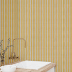 Bathroom with yellow striped wallpaper, white sink, and gold faucet.