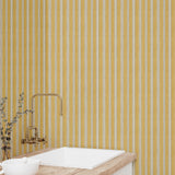 Bathroom with yellow striped wallpaper, white sink, and gold faucet.