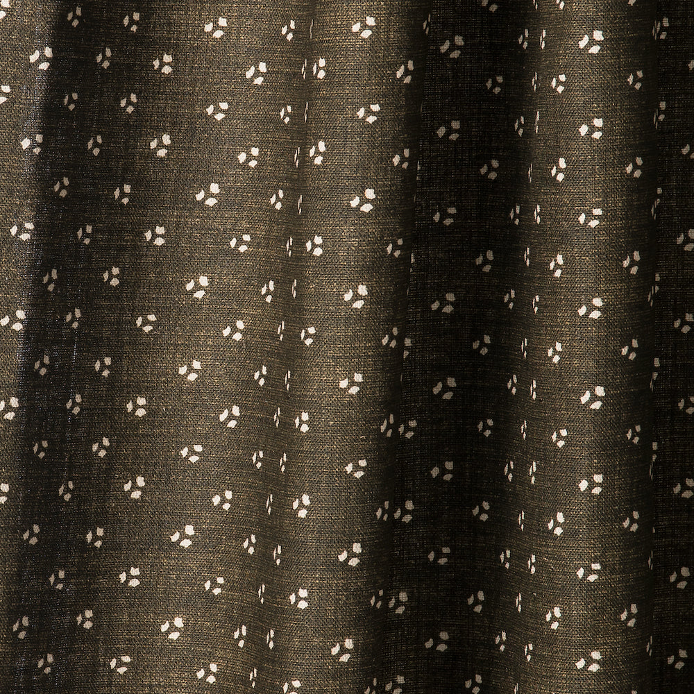 Draped printed fabric in a clustered dot pattern in cream on a dark brown field.
