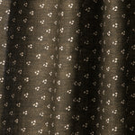 Draped printed fabric in a clustered dot pattern in cream on a dark brown field.