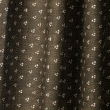 Draped printed fabric in a clustered dot pattern in cream on a dark brown field.