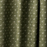 Draped printed fabric in a clustered dot pattern in cream on a moss field.