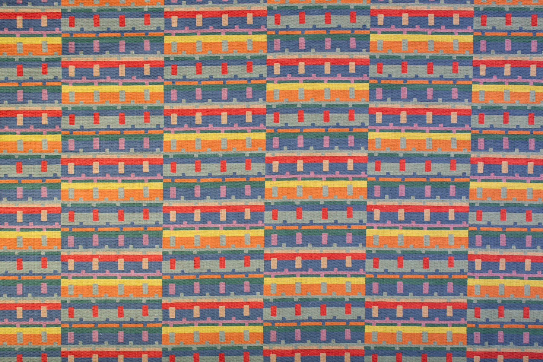 Detail of fabric in a playful geometric grid print in shades of purple, red, blue and orange.