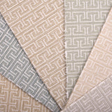 Stack of broadloom carpet samples with geometric Greek pattern in soft pastels.
