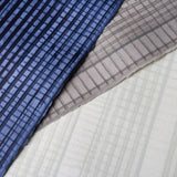 Pile of wallpaper swatches with irregular grid patterns in shades of blue, gray and cream.