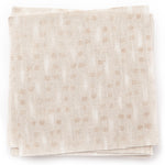 A stack of fabric swatches in a small-scale dot and dash pattern in shades of cream and white on a cream field.