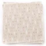 A stack of fabric swatches in a small-scale dot and dash pattern in shades of cream and white on a cream field.