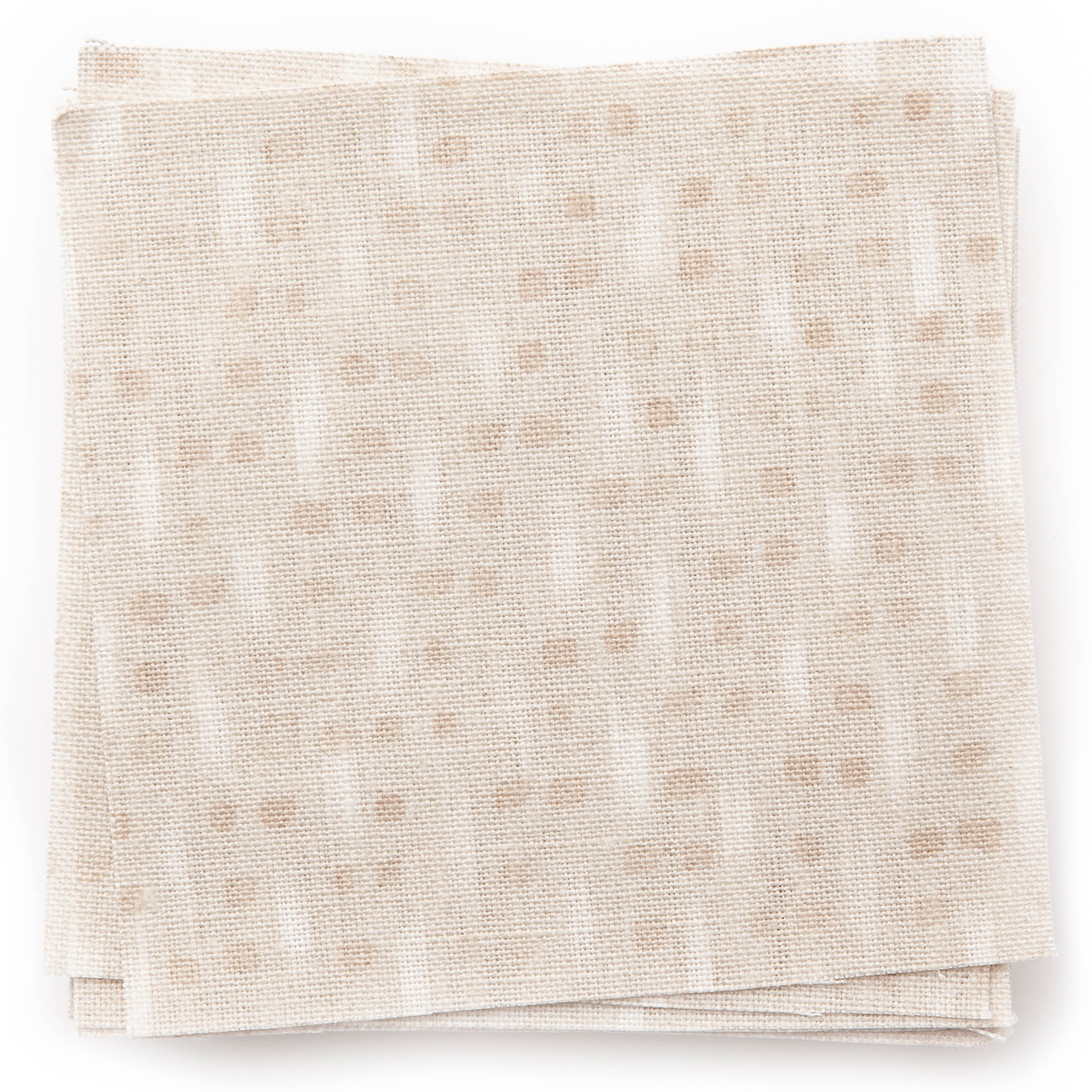 A stack of fabric swatches in a small-scale dot and dash pattern in shades of cream and white on a cream field.