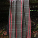 A handowven window pane fabric in brown and pink is draped in an outdoor setting. 