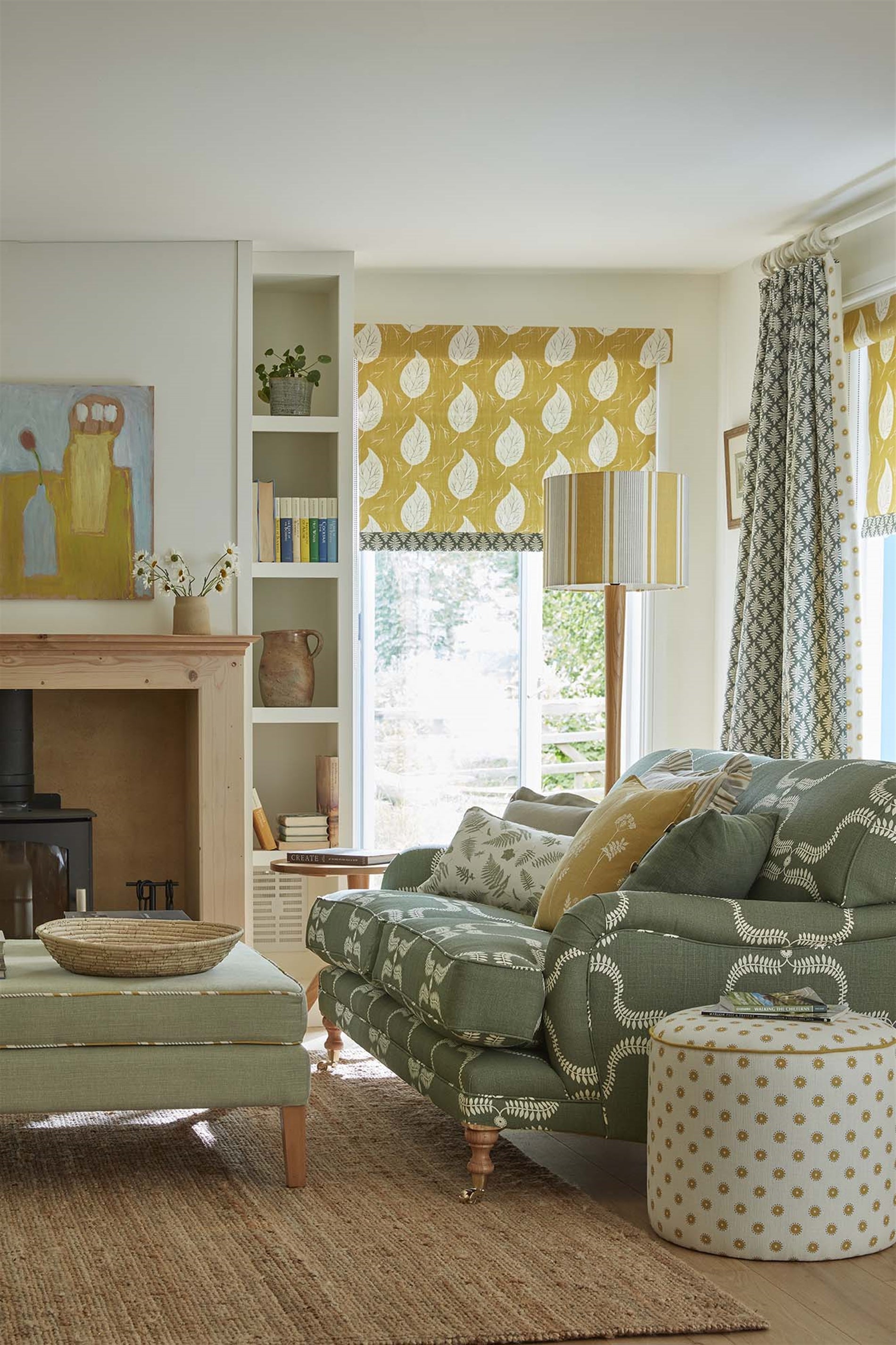 Detail of a living room with a couch upholstered in a leafy lattice print in cream on a hunter green field.