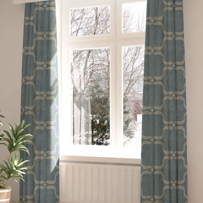 A large, sunny window with long curtains in a leafy lattice print on a blue field.