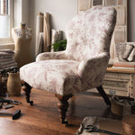 Upholstered antique chair in a purple floral design in a studio setting. 