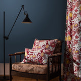 Wooden side chair with floral printed upholstery and pillows against a teal wall, with a curtain in the same floral design. 
