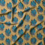 Draped fabric in a floral cameo print in blue and gray on a mustard field.