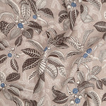 Draped fabric in a leaf and branch print in cream, brown and navy on a tan field.