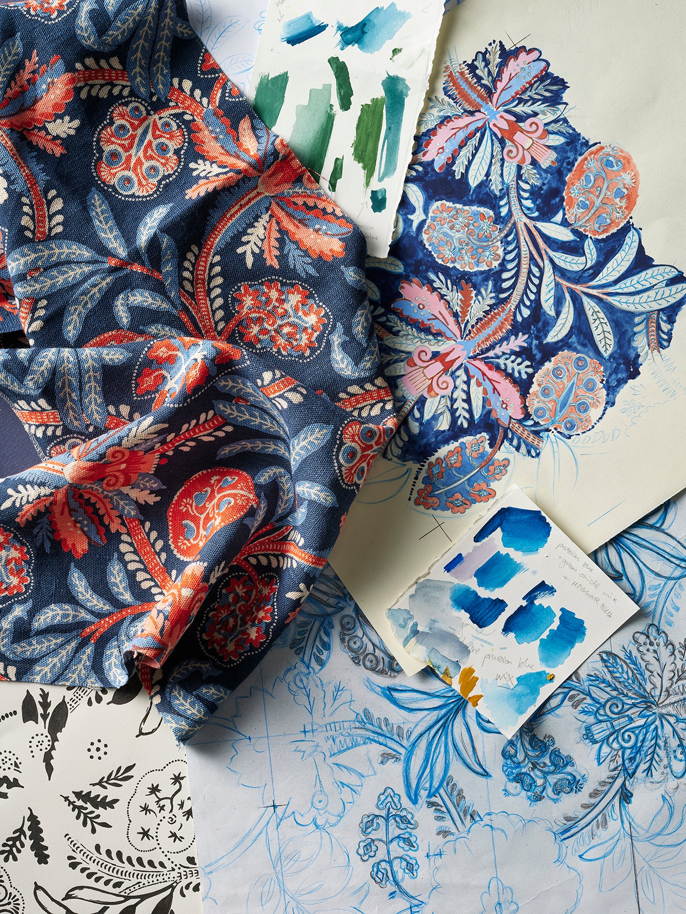 A styled flat-lay of patterned fabric and hand drawn illustrations featuring intricate botanical and floral designs in navy blue, coral red.