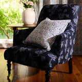 Navy floral armchair with a patterned pillow in a room with a window and curtains.