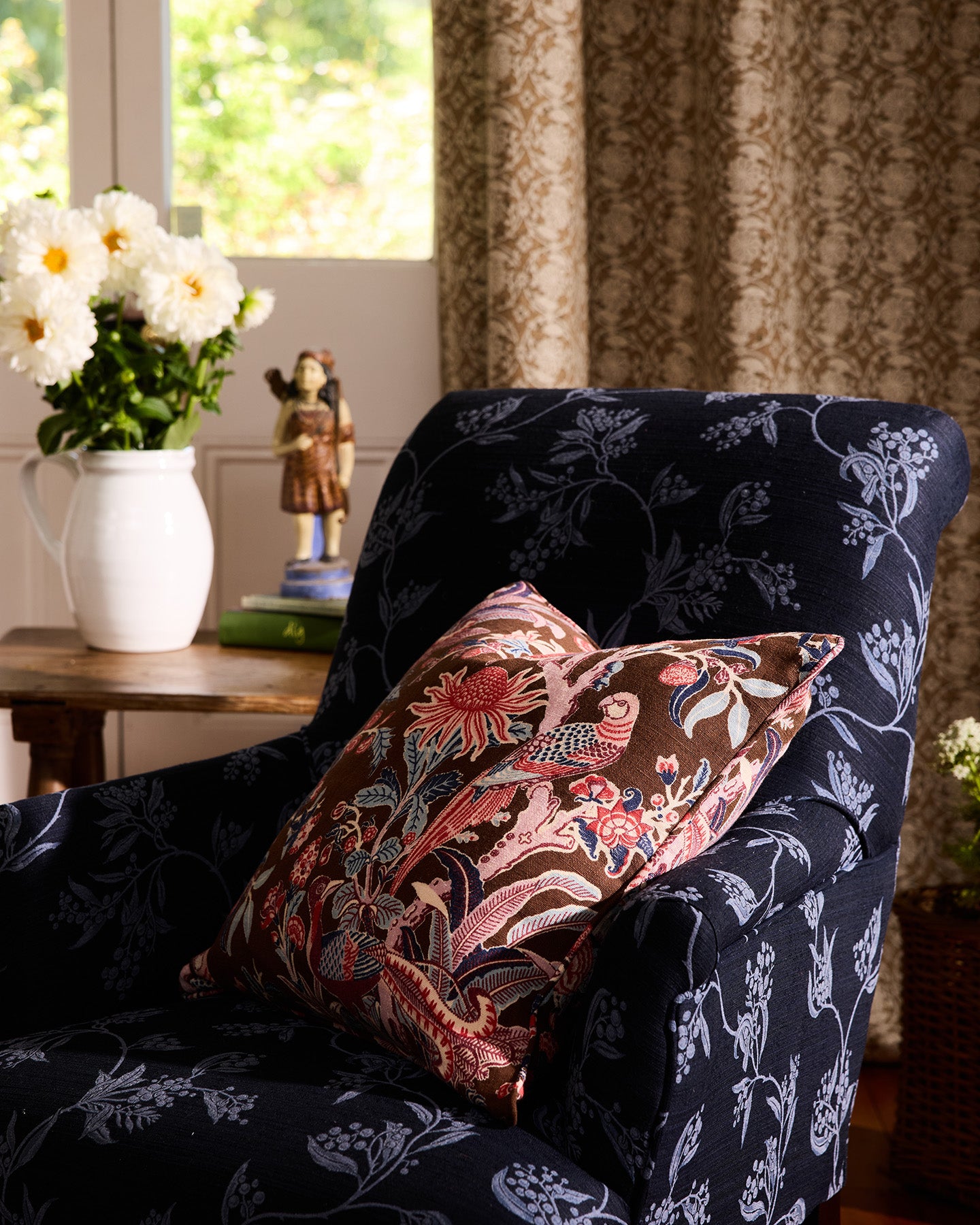 Navy armchair with floral-patterned cushions in a cozy room setting.