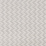 Panel of embroidered fabric in a linear geometric print in white and black on a cream field.