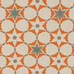 Detail of fabric in a geometric star print in shades of coral and brown on a tan field.