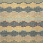 Close-up of rug with wavy pattern in beige, turquoise, and orange.