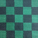 A close-up handwoven rug in a checkerboard pattern in black and green