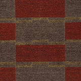 Detail of a handwoven carpet in a geometric design in brown, red with yellow accent. 