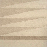 Detail of a handwoven rug in a geometric design in shades of beige. 