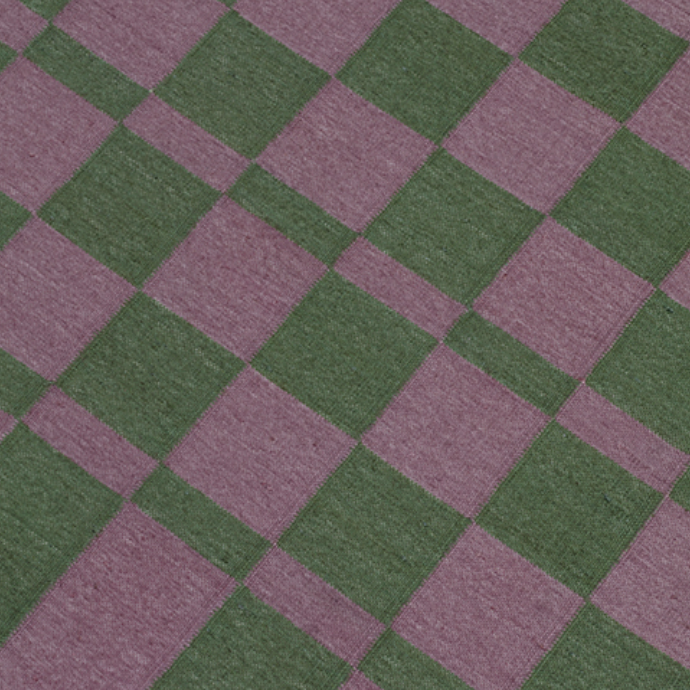 Detail of dhurrie rug in a checkerboard pattern of green and purple