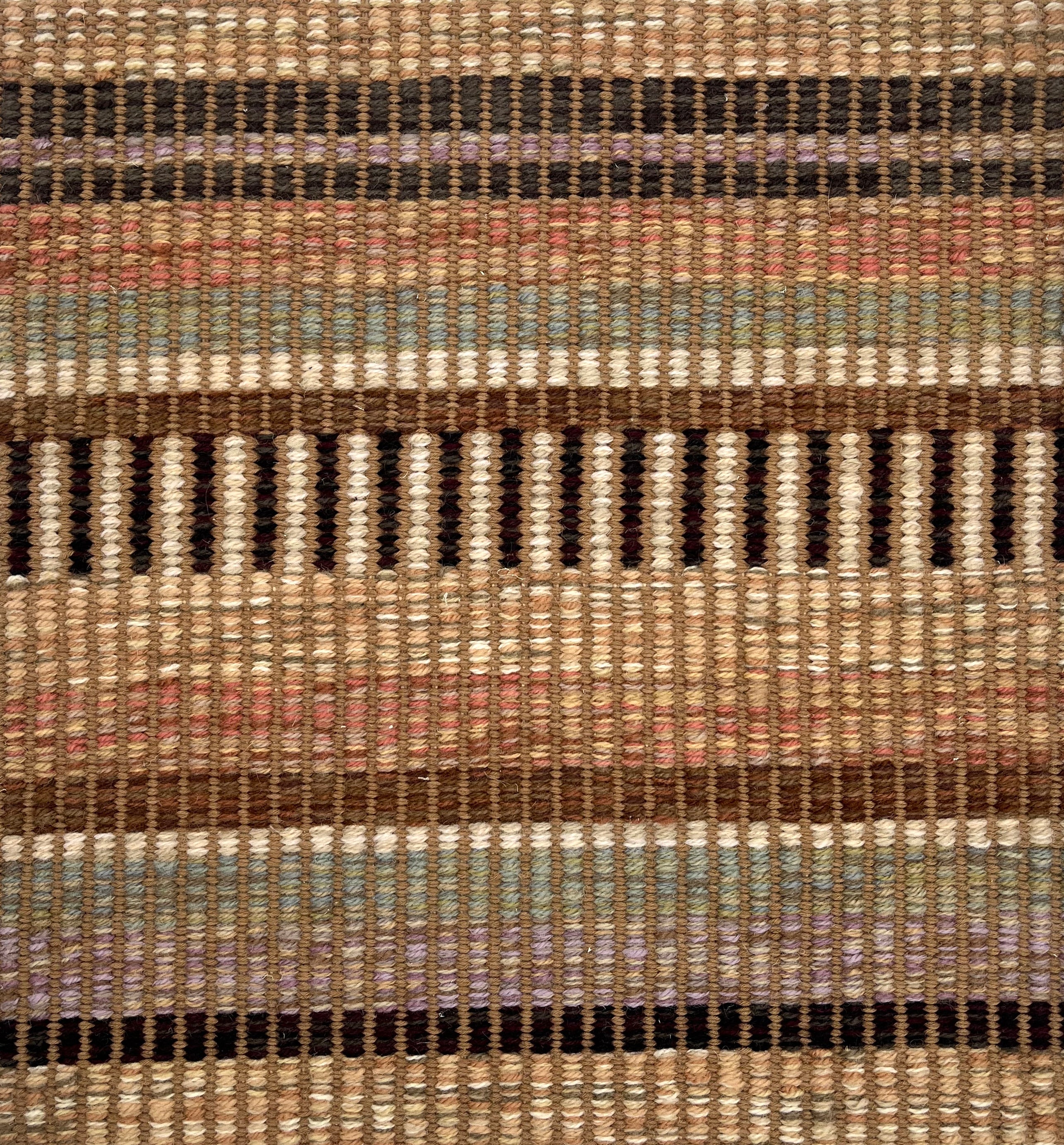 Handwoven rug detail in a stripe design in blue, white, red, blue, purple 