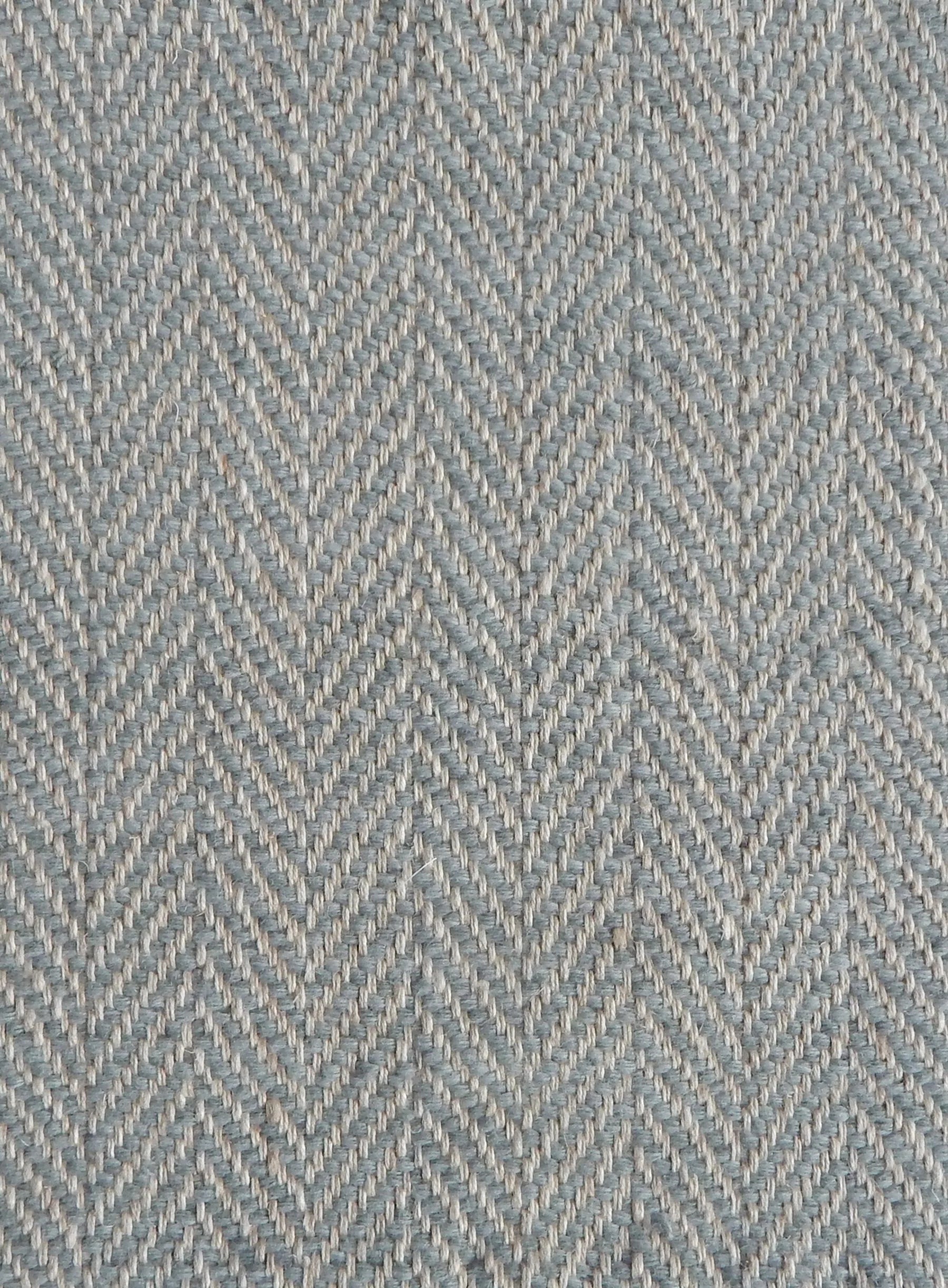 Close up of a rug in a woven herringbone pattern in grey-blue.
