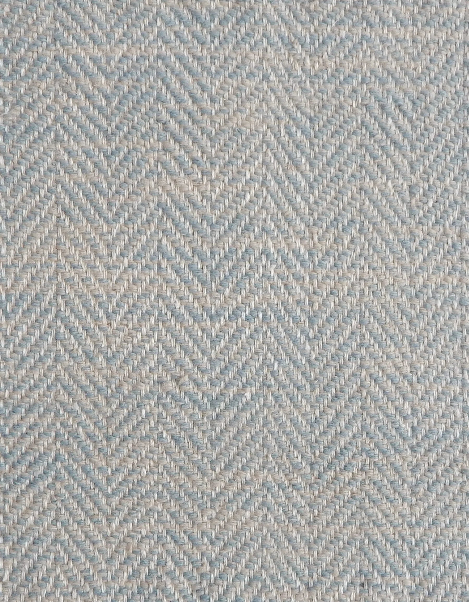 Close up of a rug in a woven herringbone pattern in light blue.