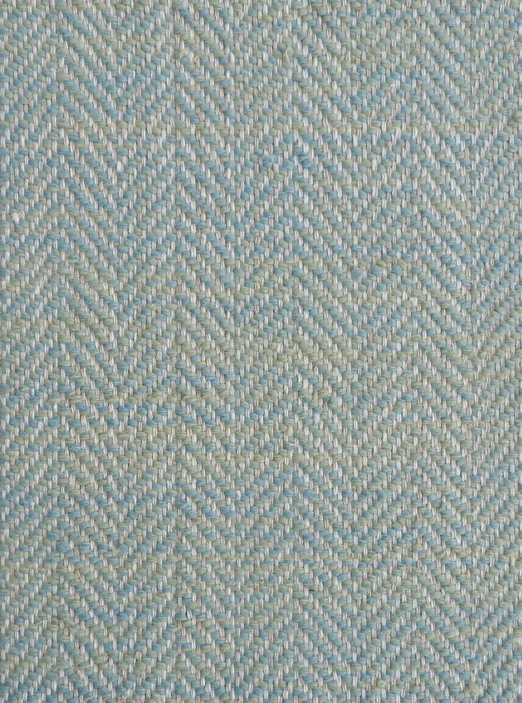 Close up of a rug in a woven herringbone pattern in aqua blue.