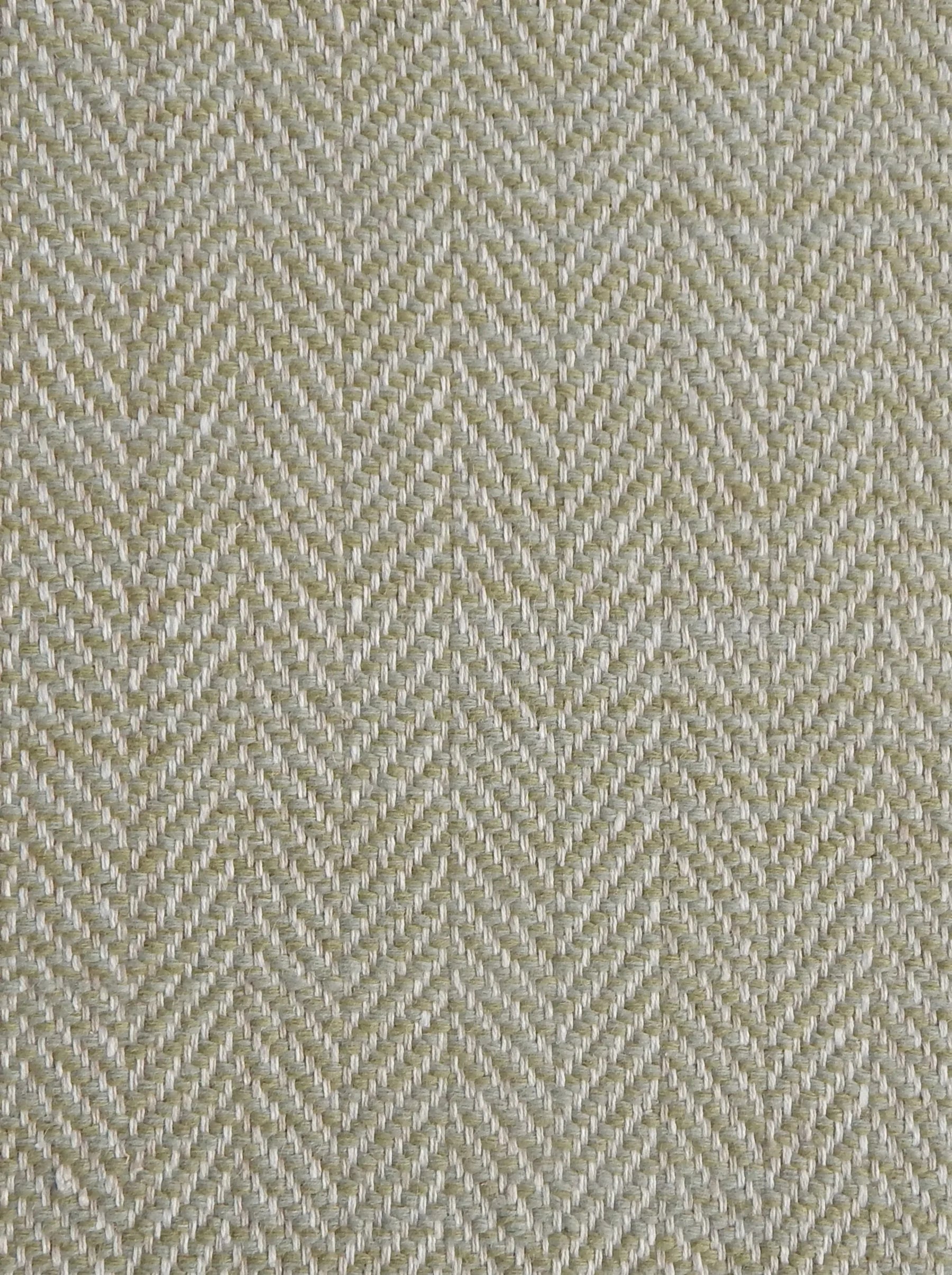 Close up of a rug in a woven herringbone pattern in light green.