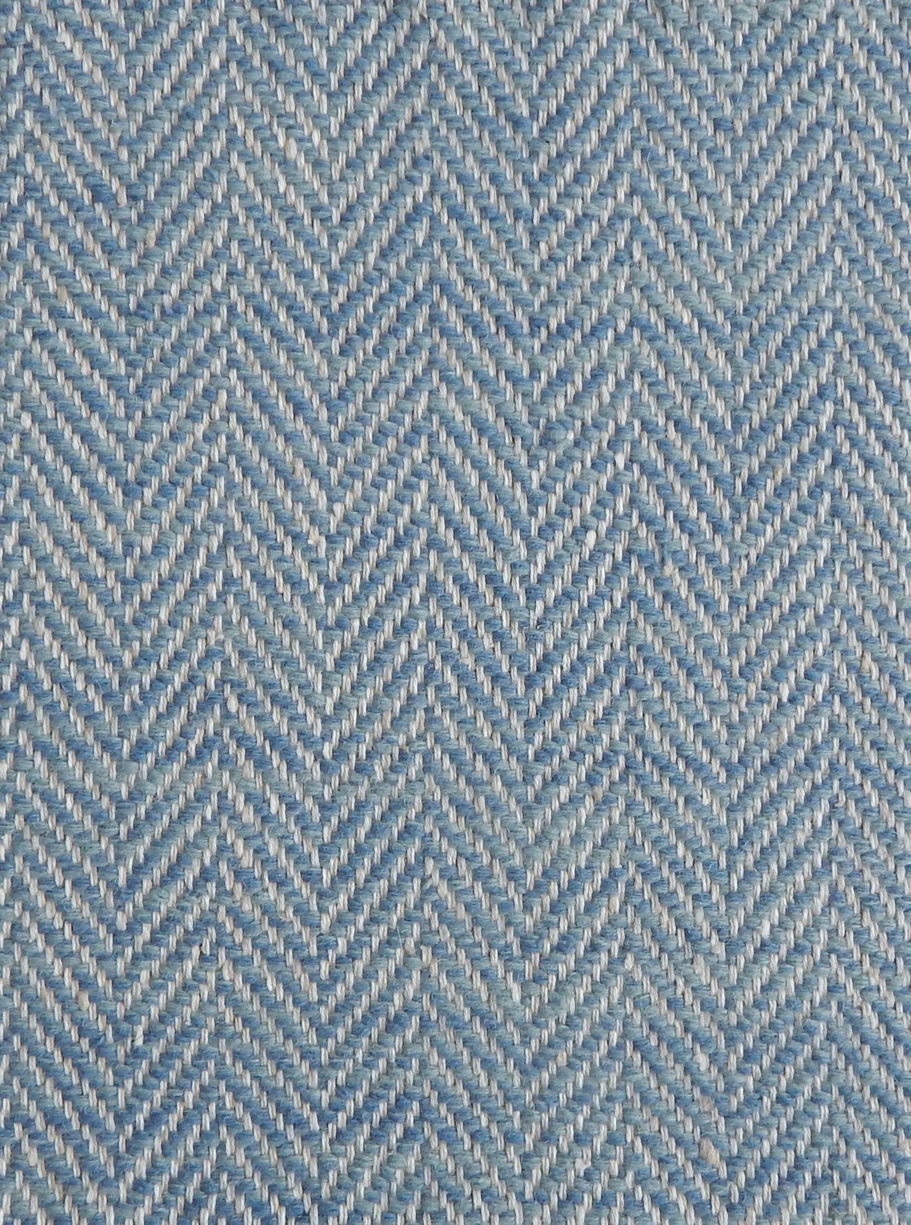 Close up of a rug in a woven herringbone pattern in blue.