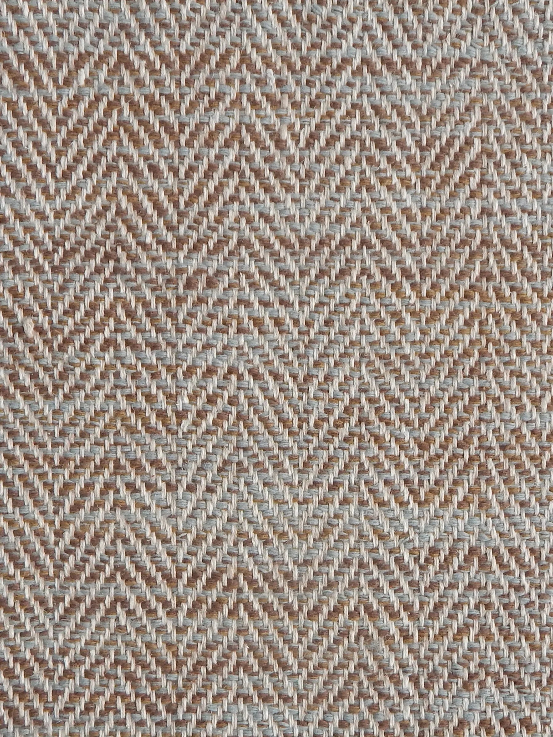 Close up of a rug in a woven herringbone pattern in blue and brown. 