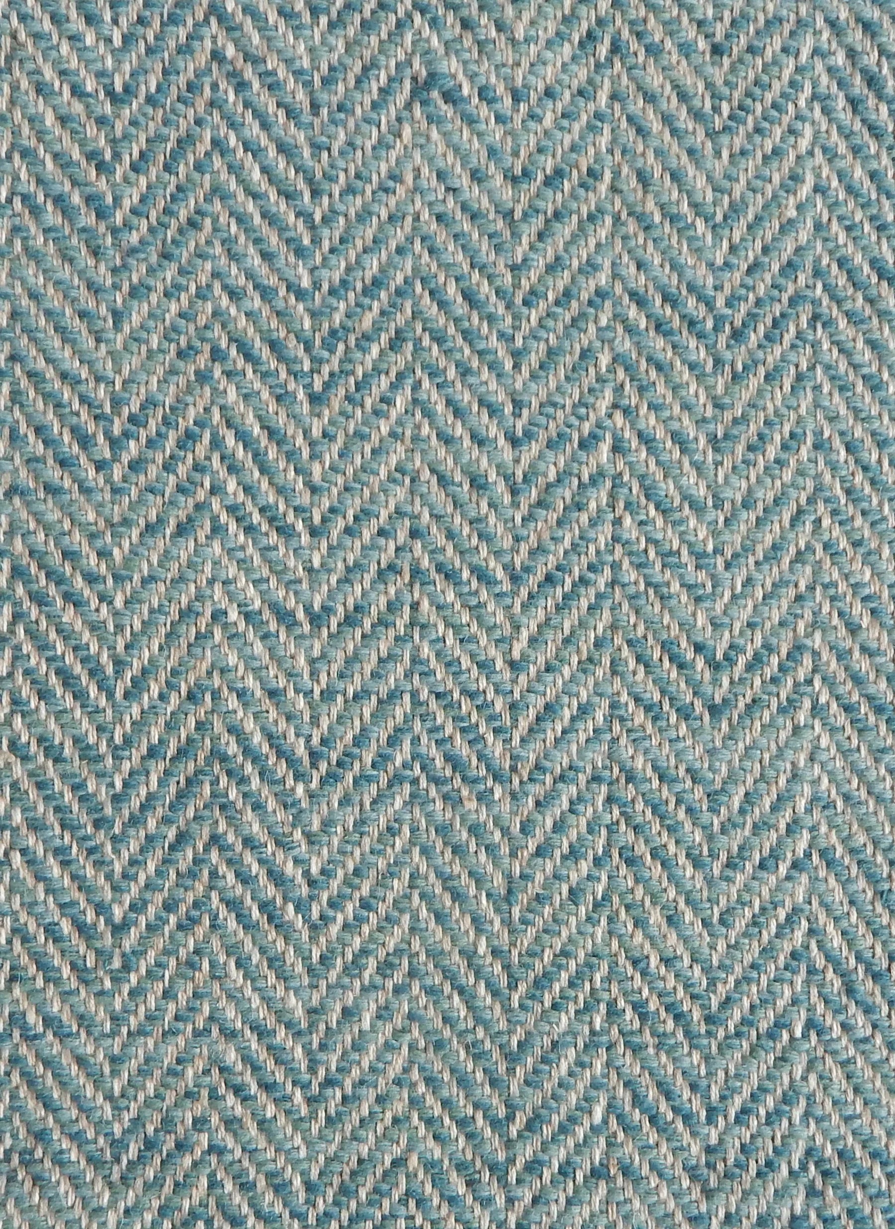 Close up of a rug in a woven herringbone pattern in turquouise.