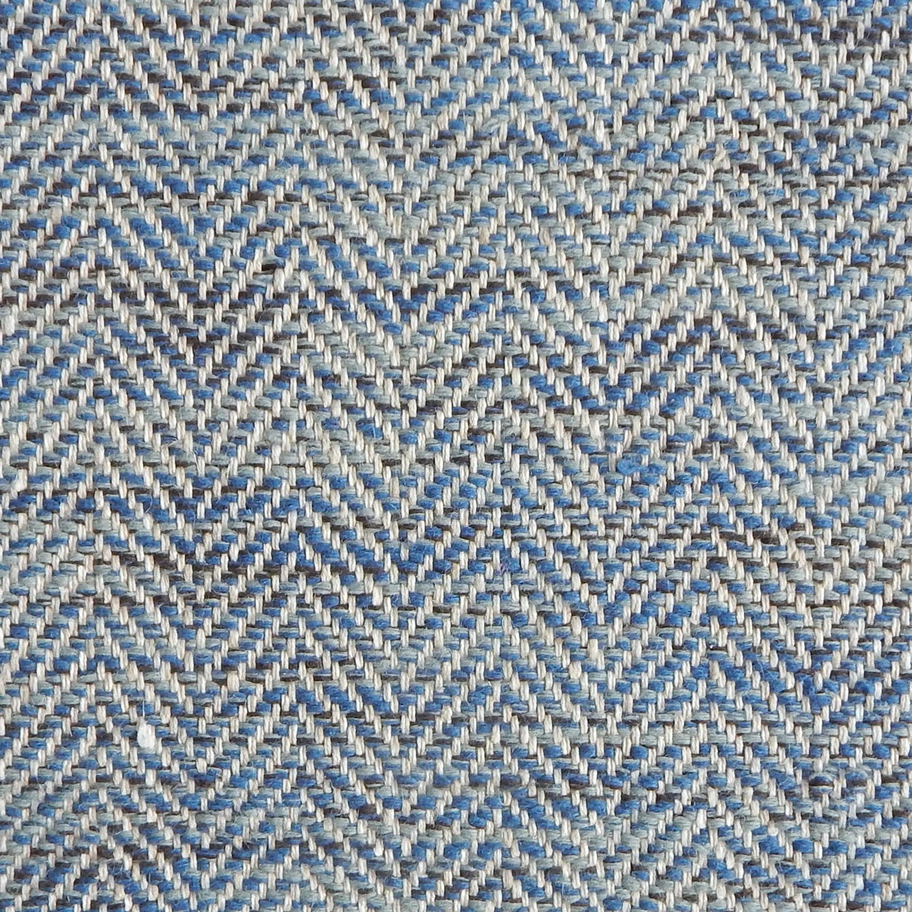 Close up of a rug in a woven herringbone pattern in blues.