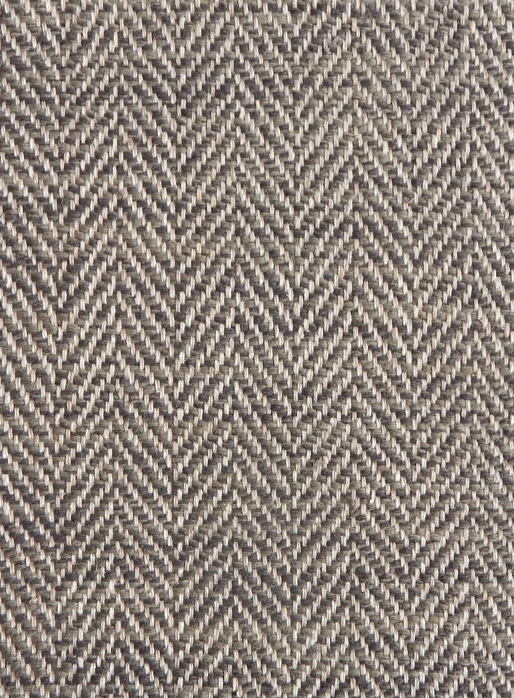 Close up of a rug in a woven herringbone pattern in grey and brown.