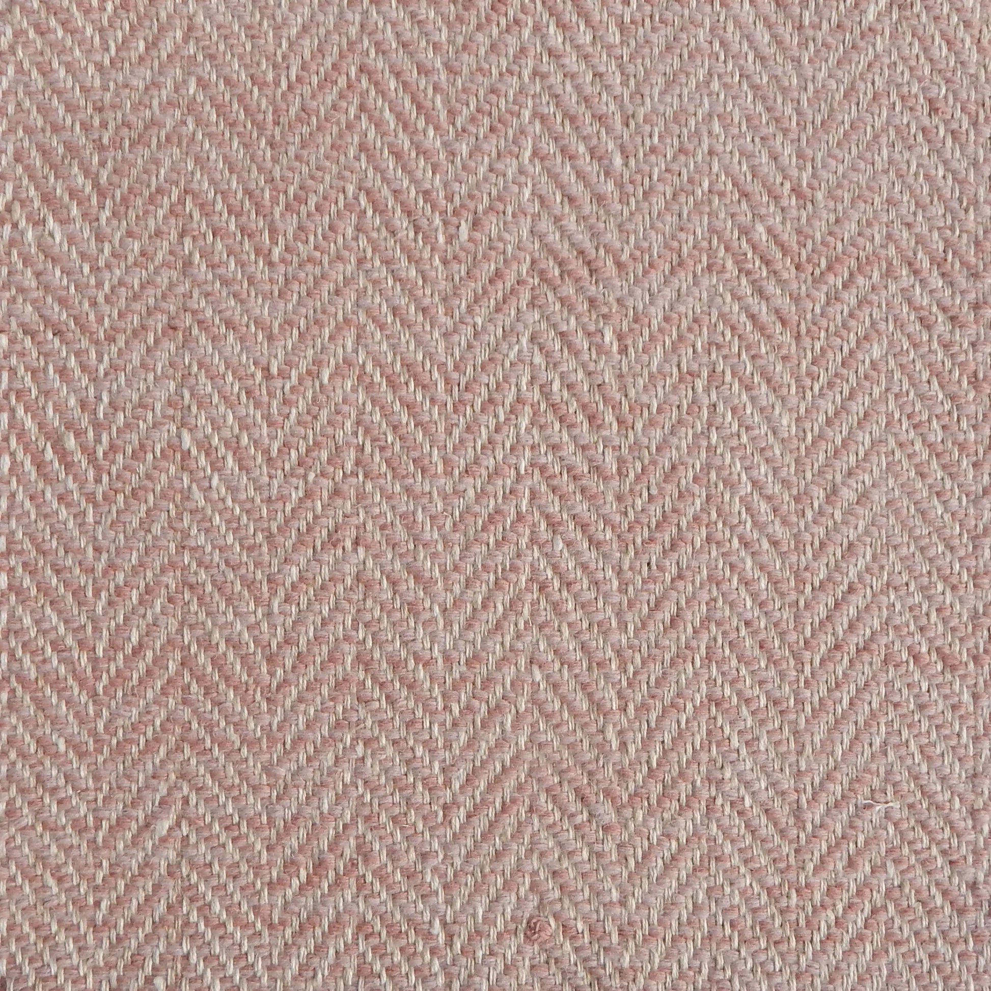 Close up of a rug in a woven herringbone pattern in light pink