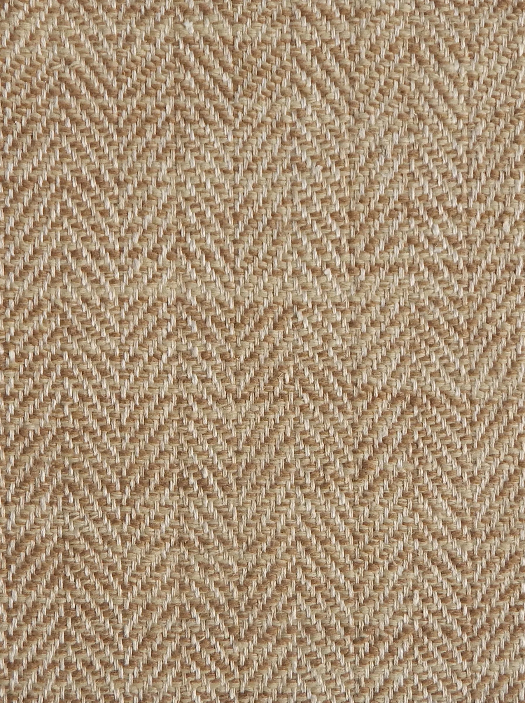 Close up of a rug in a woven herringbone pattern in tan.