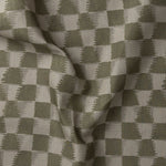 Detail of gently draped printed fabric in a watercolor ikat-inspired checkerboard pattern in tonal muted olive green.