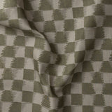 Detail of gently draped printed fabric in a watercolor ikat-inspired checkerboard pattern in tonal muted olive green.