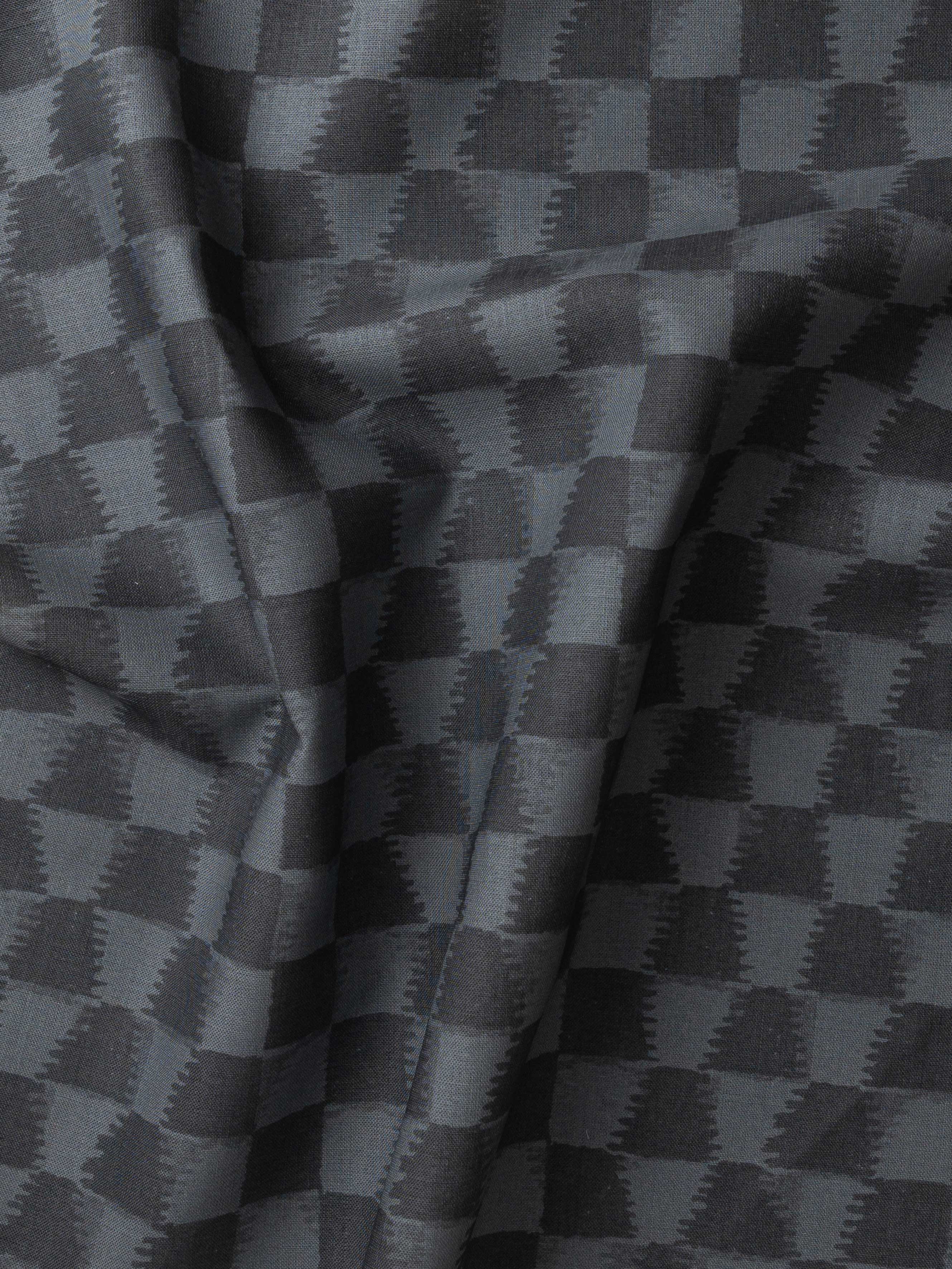 Detail of gently draped printed fabric in a watercolor ikat-inspired checkerboard pattern in tonal navy blue. 