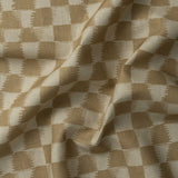 Detail of gently draped printed fabric in a watercolor ikat-inspired checkerboard pattern in warm tan.