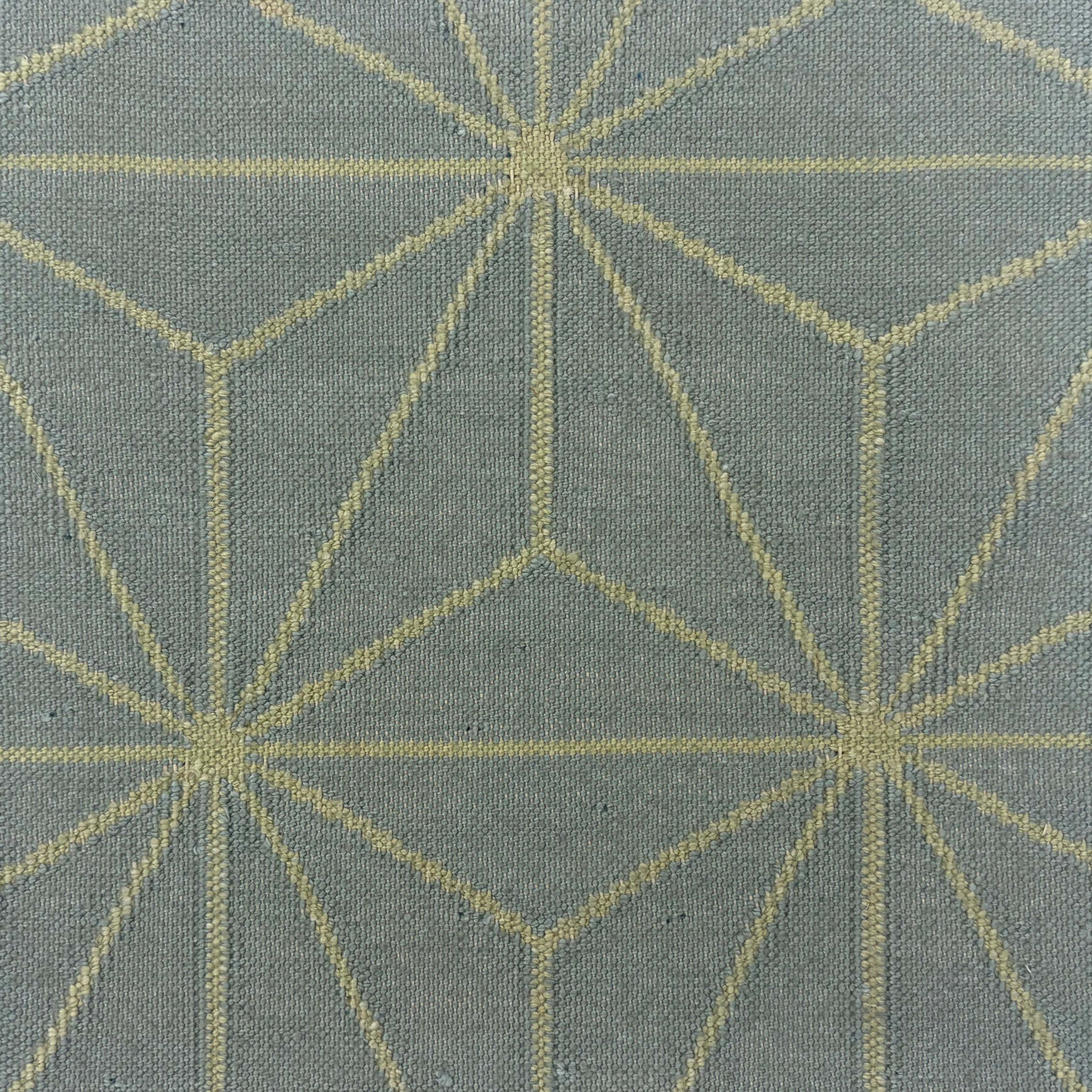 Handmade flatweave rug with linear star lattice design in cream on a light blue field.