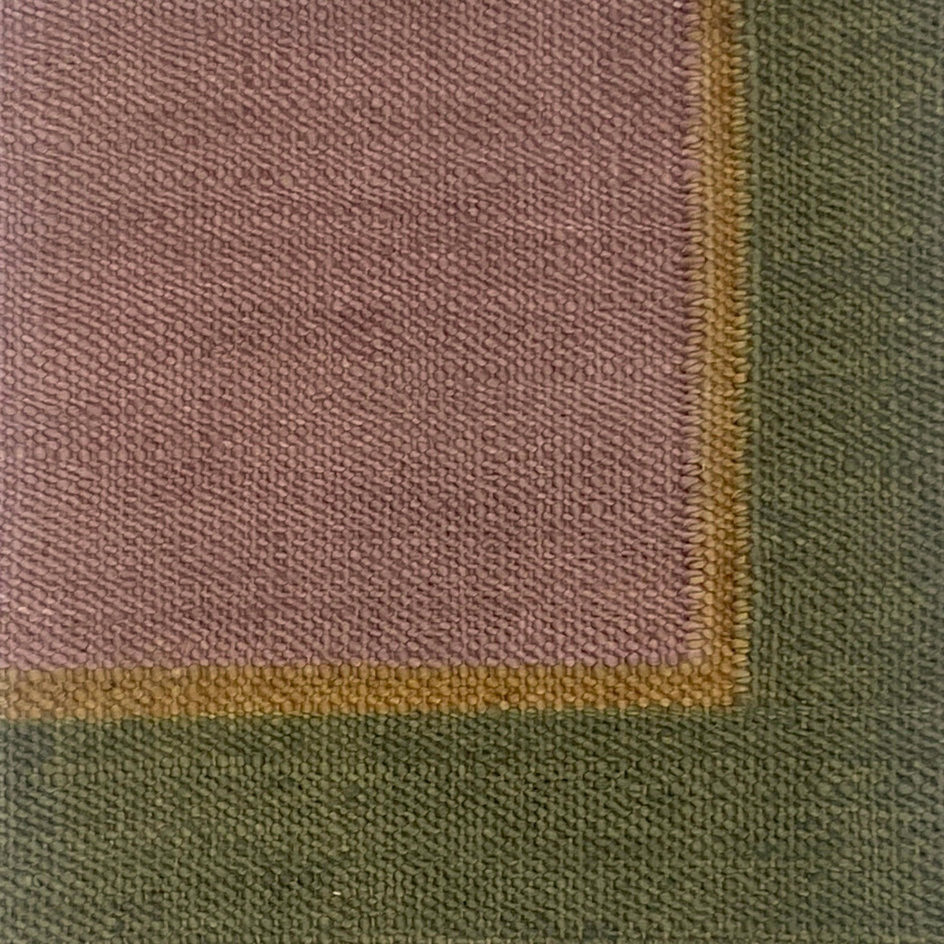 Close up of a flatweave rug in light purple with tan and green border. 