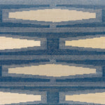 Close up of a handmade flatweave rug with a geometric tiled design in cream and shades of blue. 